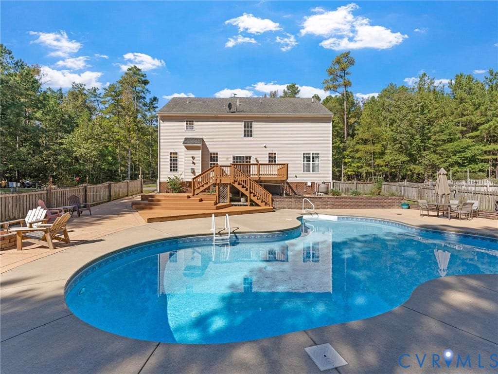 Two-story exterior with multi-level wood deck, freeform swimming pool, and concrete patio
