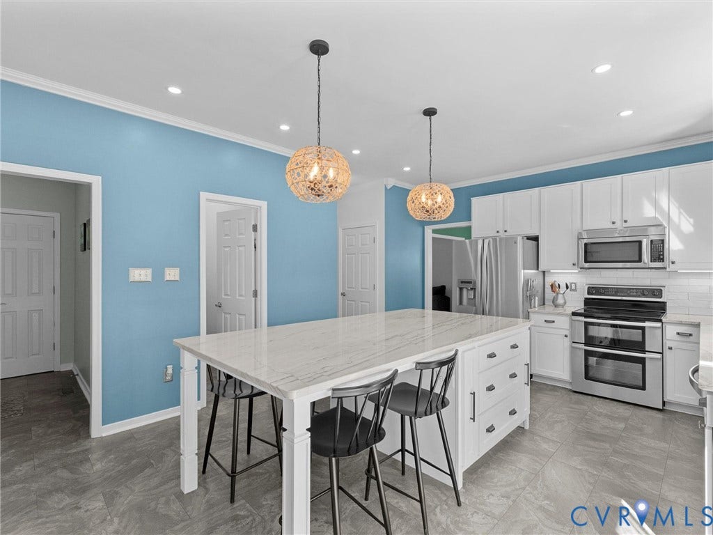 Kitchen featuring a large center island with a stone countertop, white cabinetry, stainless steel appliances, and pendant lighting