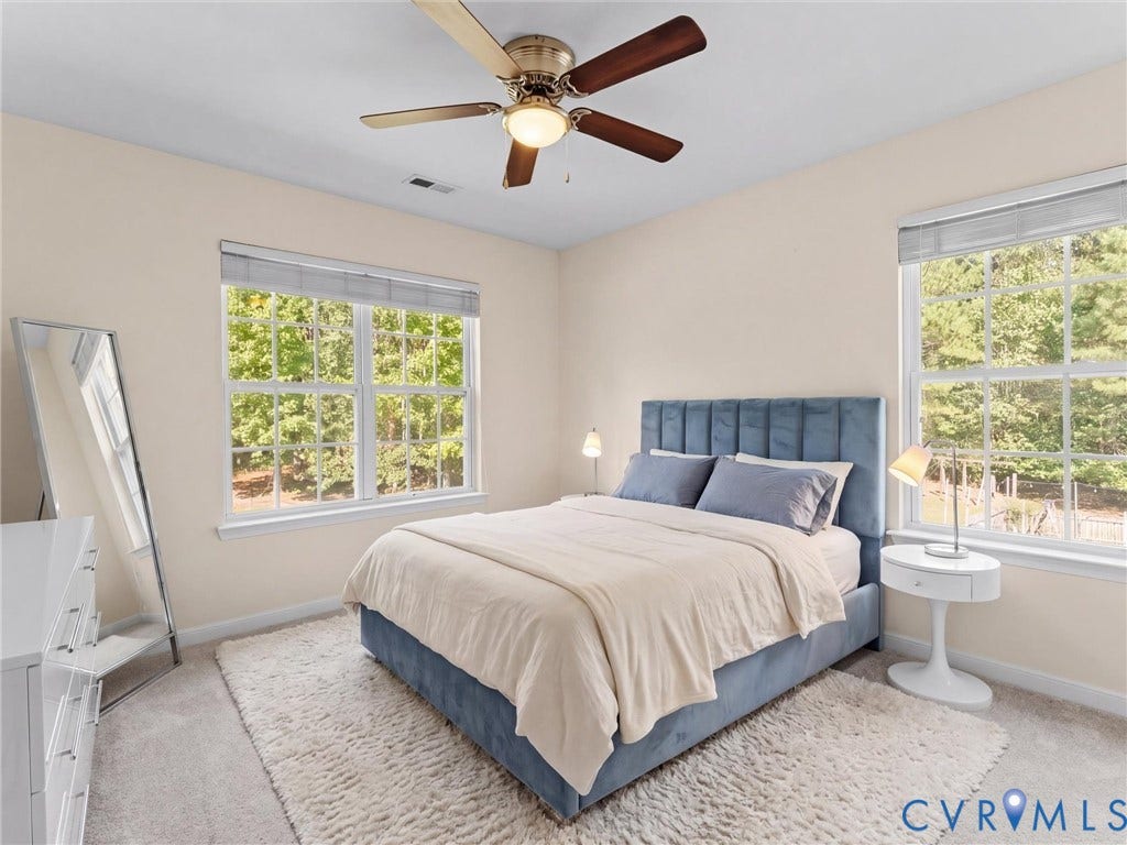 Carpeted room featuring two multi-pane windows, a ceiling fan with light, and light-colored wall paint