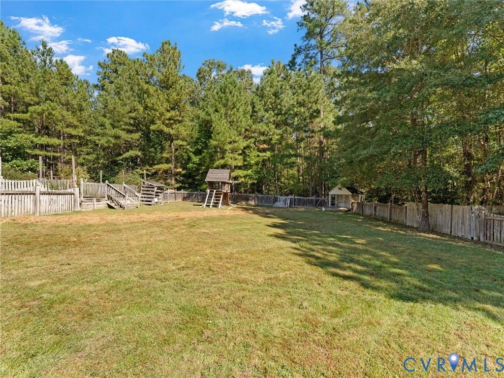 Expansive fenced yard with natural tree surroundings and a small shed structure