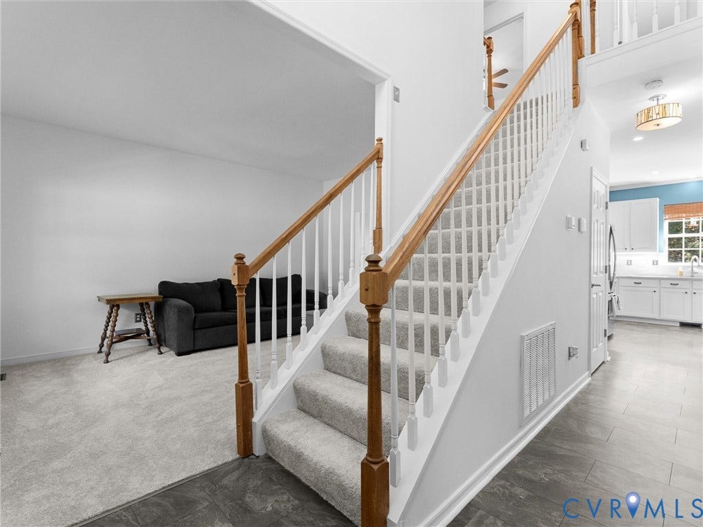 Carpeted staircase with wood handrails and white balusters