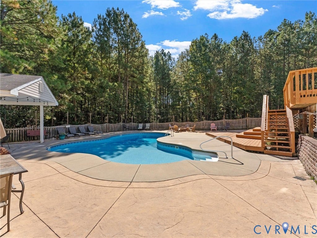 Curved inground pool with concrete surround, multi-level wood deck, and an attached wood gazebo