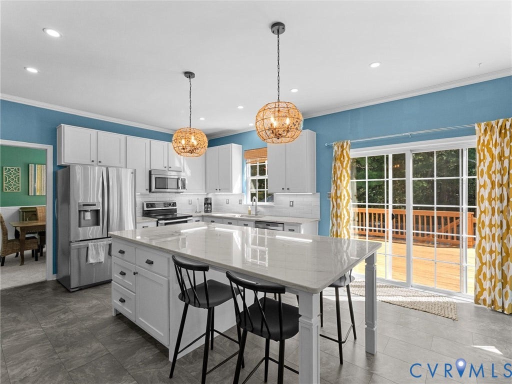 Kitchen featuring a center island with seating, stainless steel appliances, white cabinetry, and recessed lighting