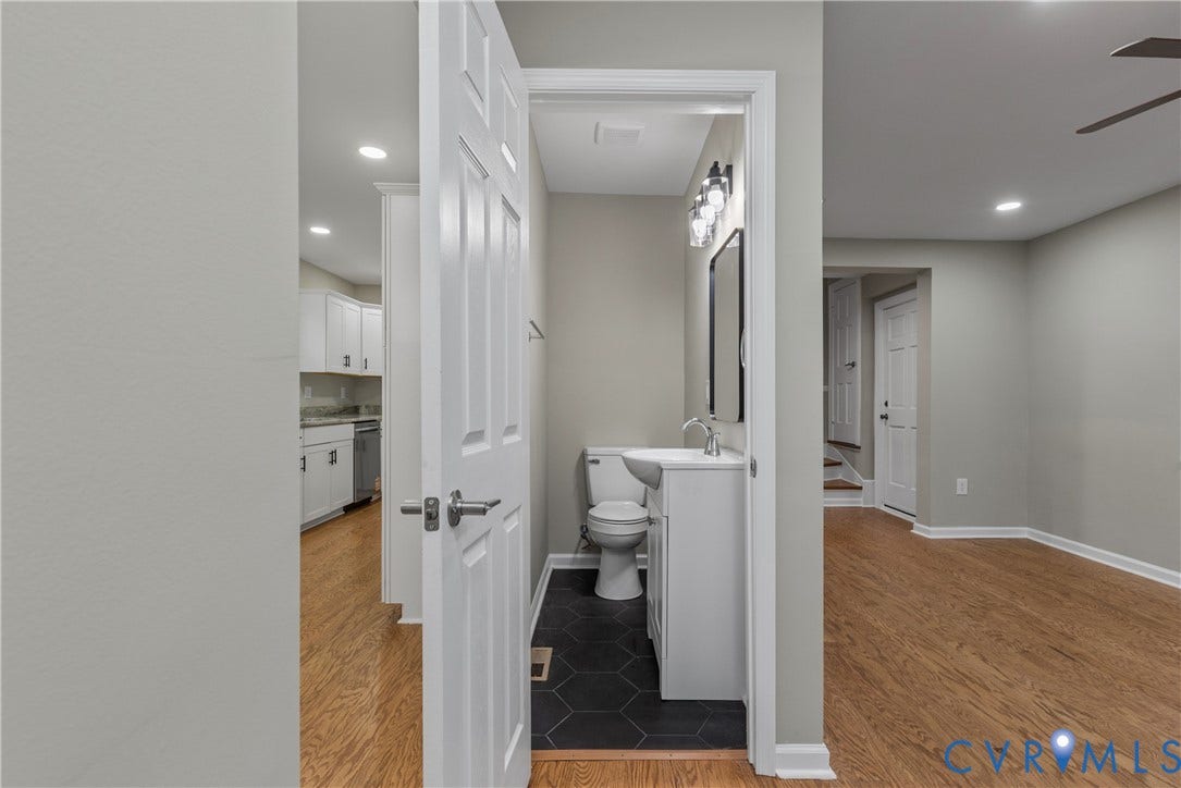 2606 Hawthorne Avenue, Richmond, VA 23222 Powder room featuring a white vanity with integrated sink, black hexagonal floor tiles, and a contemporary light fixture