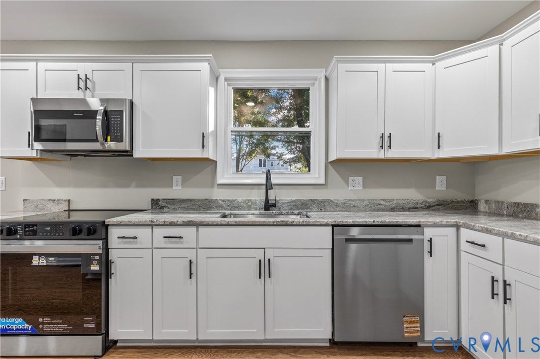 2606 Hawthorne Avenue, Richmond, VA 23222 White shaker-style cabinetry with matte black hardware, granite countertops, stainless steel appliances, and a window above the sink