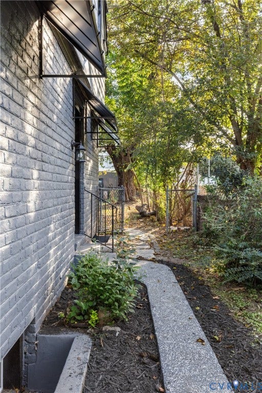 2606 Hawthorne Avenue, Richmond, VA 23222 Painted brick exterior with multiple window awnings, a concrete pathway, a metal handrail, and mature trees