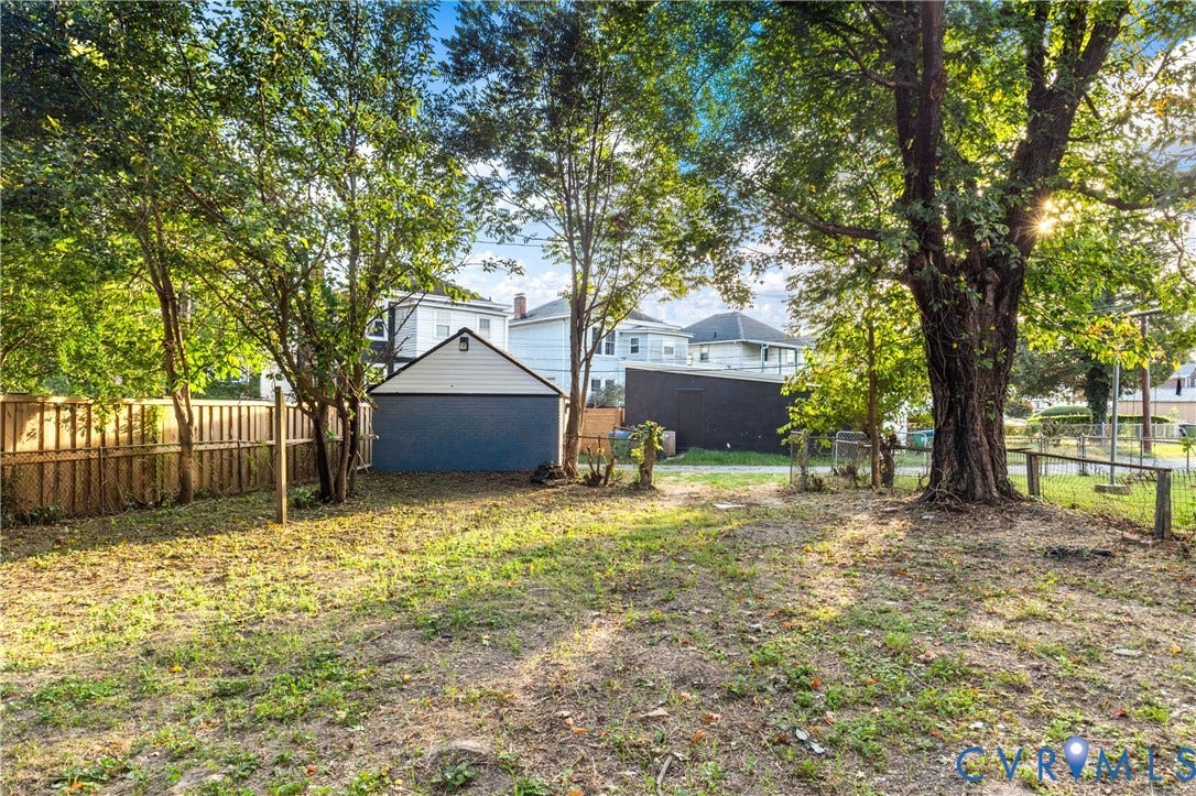 2606 Hawthorne Avenue, Richmond, VA 23222 Expansive backyard featuring mature trees, a wood privacy fence, and a detached structure with a gable roof