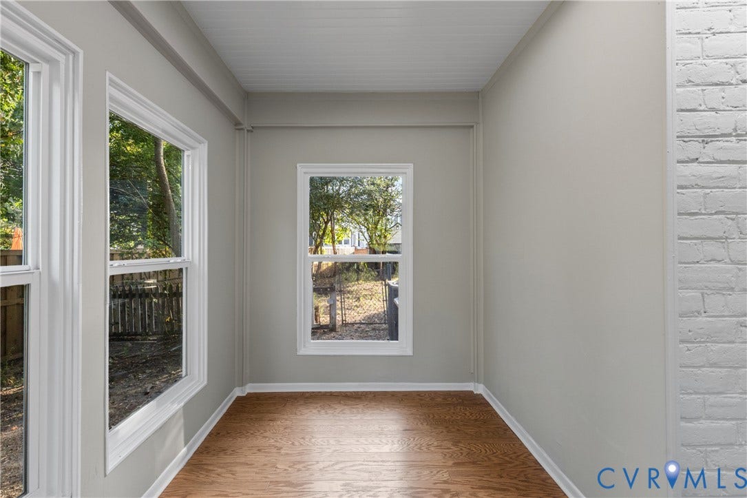2606 Hawthorne Avenue, Richmond, VA 23222 Wood-finish flooring, multiple windows, white window trim, light-toned wall paint, and a white brick wall