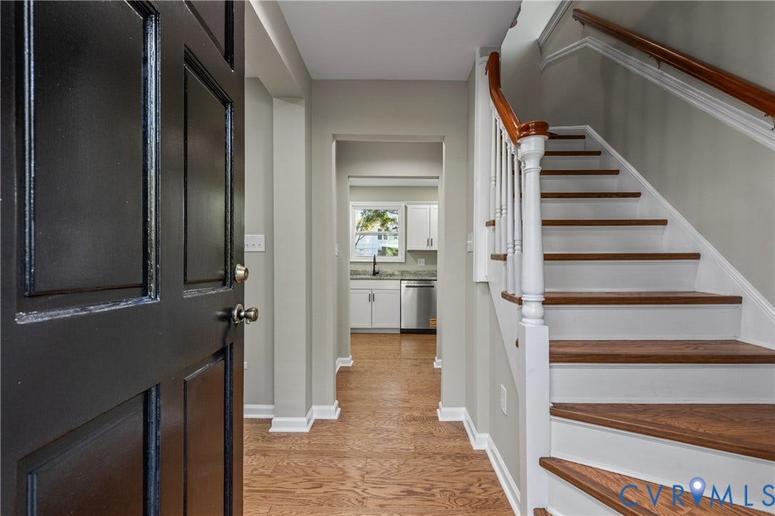2606 Hawthorne Avenue, Richmond, VA 23222 Hardwood flooring, painted paneled door, staircase with wood treads and handrail, and white kitchen cabinetry with stainless steel appliances