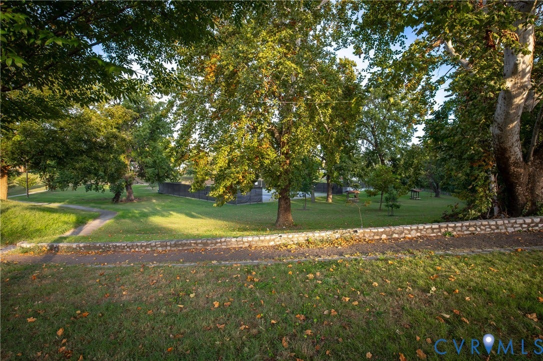 2606 Hawthorne Avenue, Richmond, VA 23222 Expansive lawn area with a stone retaining wall, mature trees, and a paved pathway