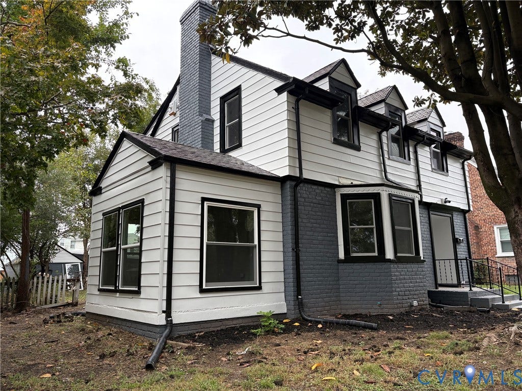 2606 Hawthorne Avenue, Richmond, VA 23222 White siding exterior with black trim, gray brick foundation, multiple dormer windows, and a prominent gray-painted brick chimney