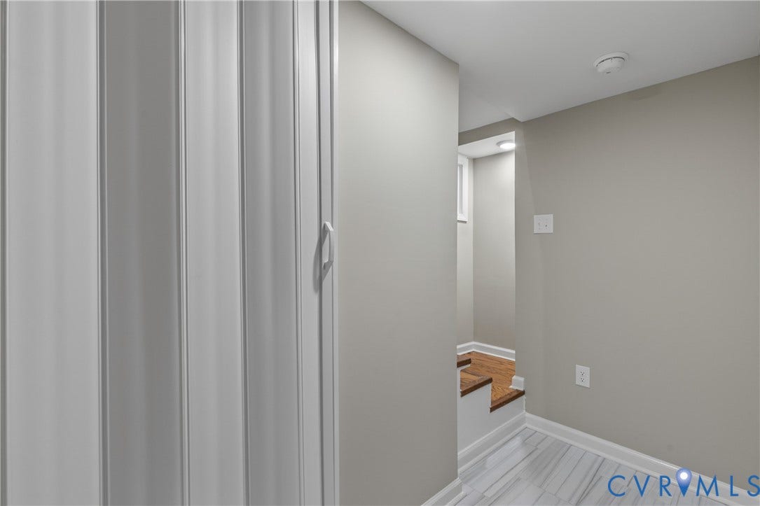 2606 Hawthorne Avenue, Richmond, VA 23222 White accordion door, light gray painted walls, tile flooring with linear veining, wood-finish stair treads, and white trim throughout