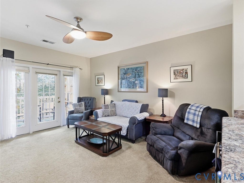 Plush carpet flooring, ceiling fan with integrated lighting, light neutral wall paint, double French doors, and granite-look countertop