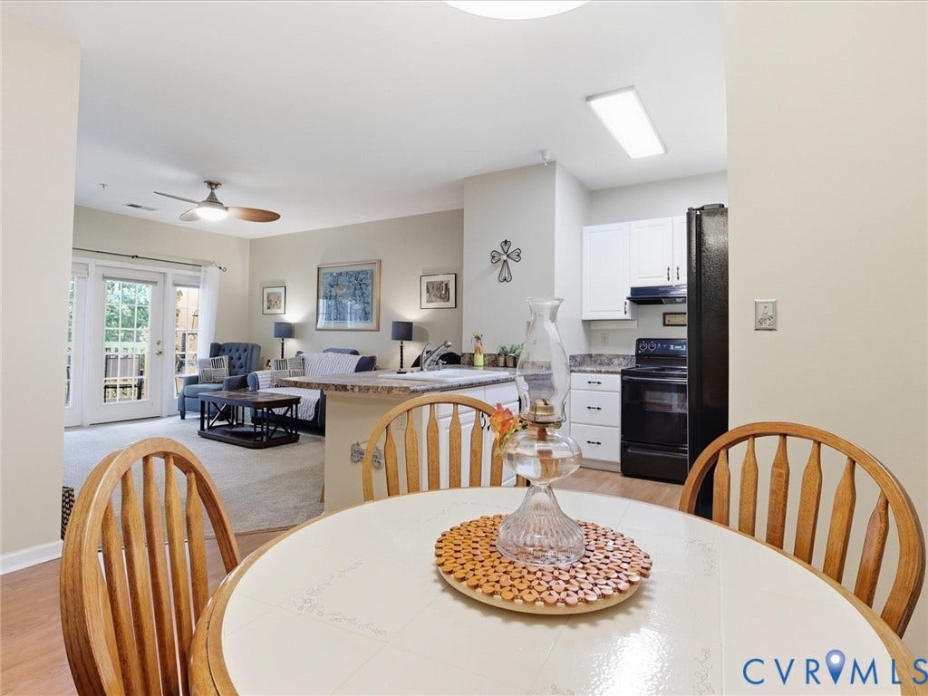 Kitchen area with white cabinetry, black appliances, and stone-finish countertops