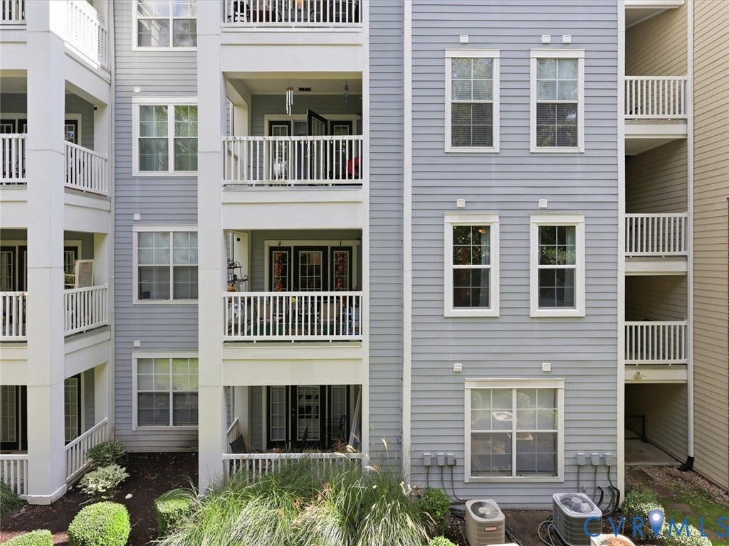 Exterior featuring horizontal siding, multiple balconies with white railings, double-hung windows, and foundational landscaping