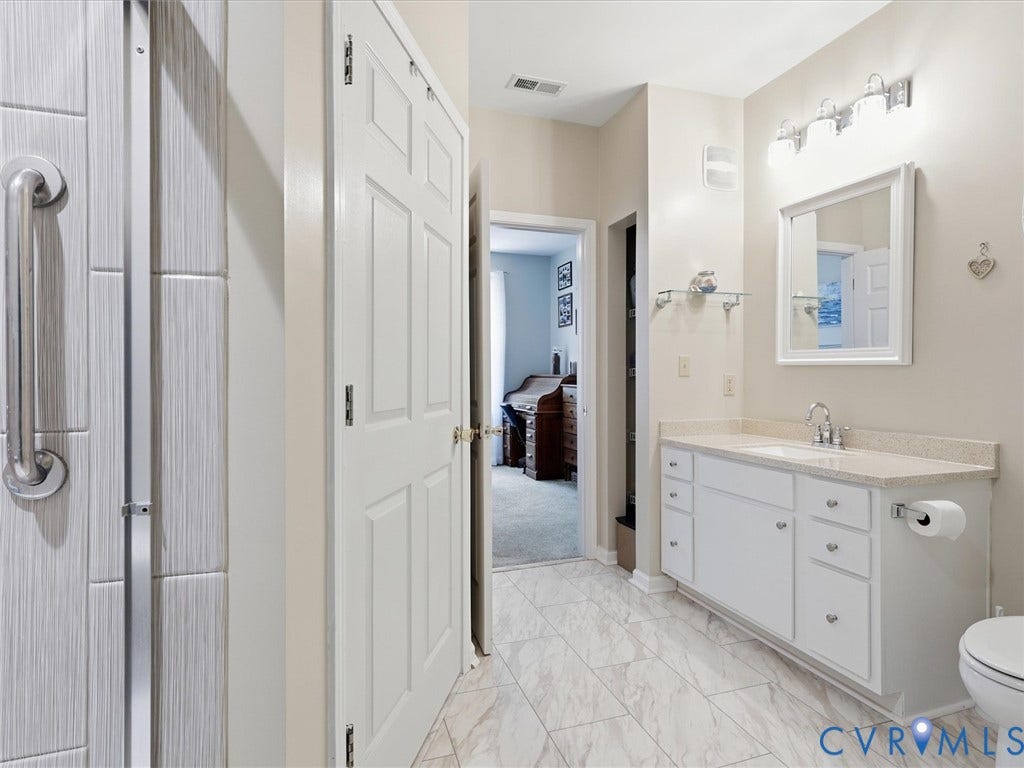 White cabinetry vanity with a light-toned countertop, rectangular sink, and chrome faucet