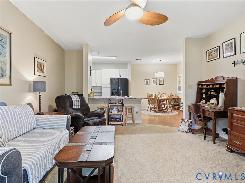 Carpeted living area with a ceiling fan, recessed lighting, and a breakfast bar