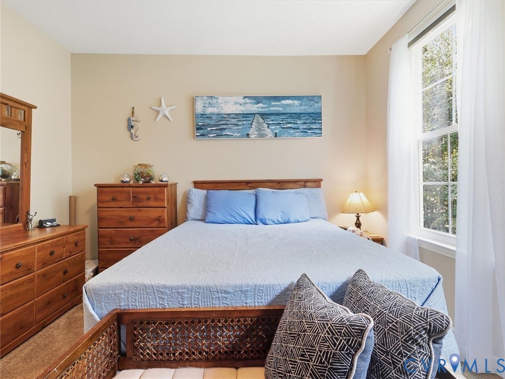 Large window with white sheers, wood-finish flooring, and neutral wall tones