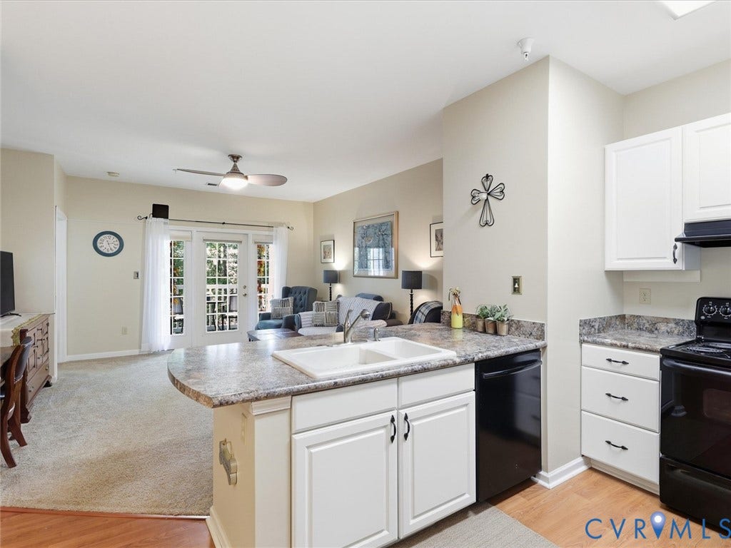Kitchen with white cabinetry, black appliances, a double basin sink, and a peninsula with a stone-finish countertop