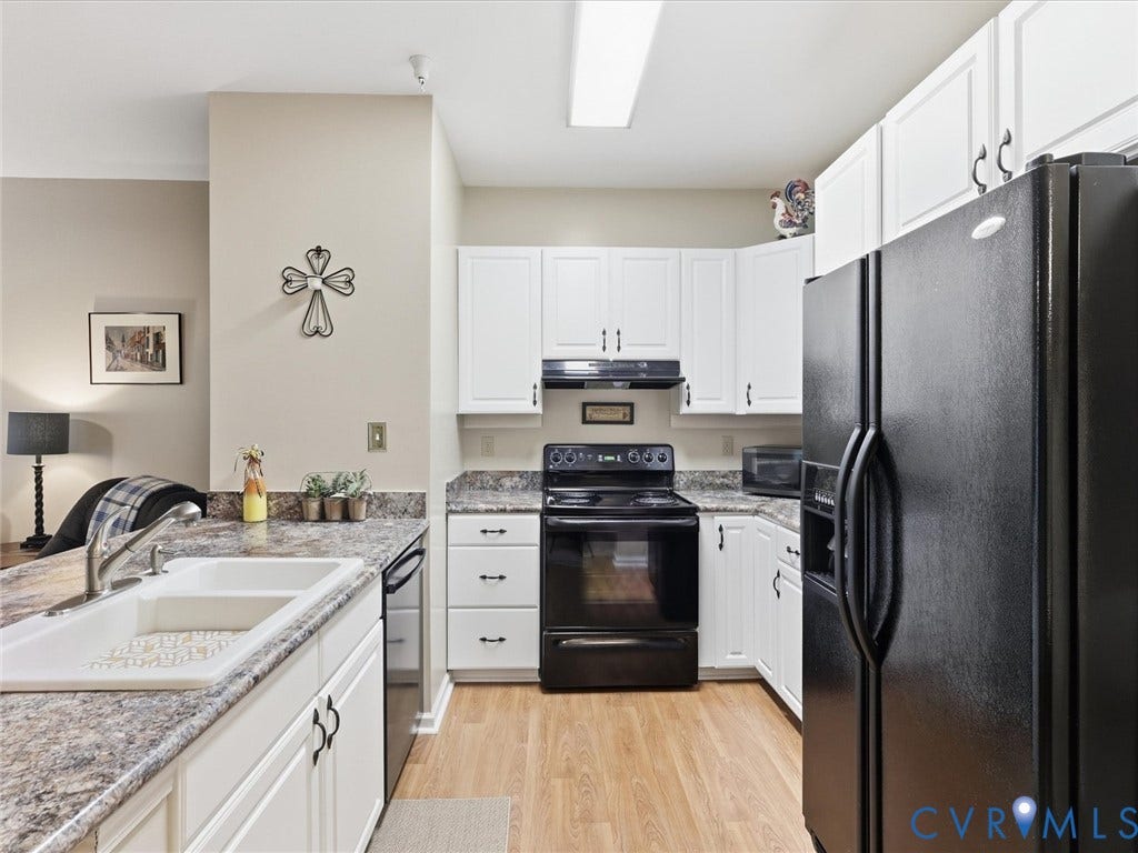 Kitchen featuring white cabinetry, wood-finish flooring, a white drop-in sink, and black appliances
