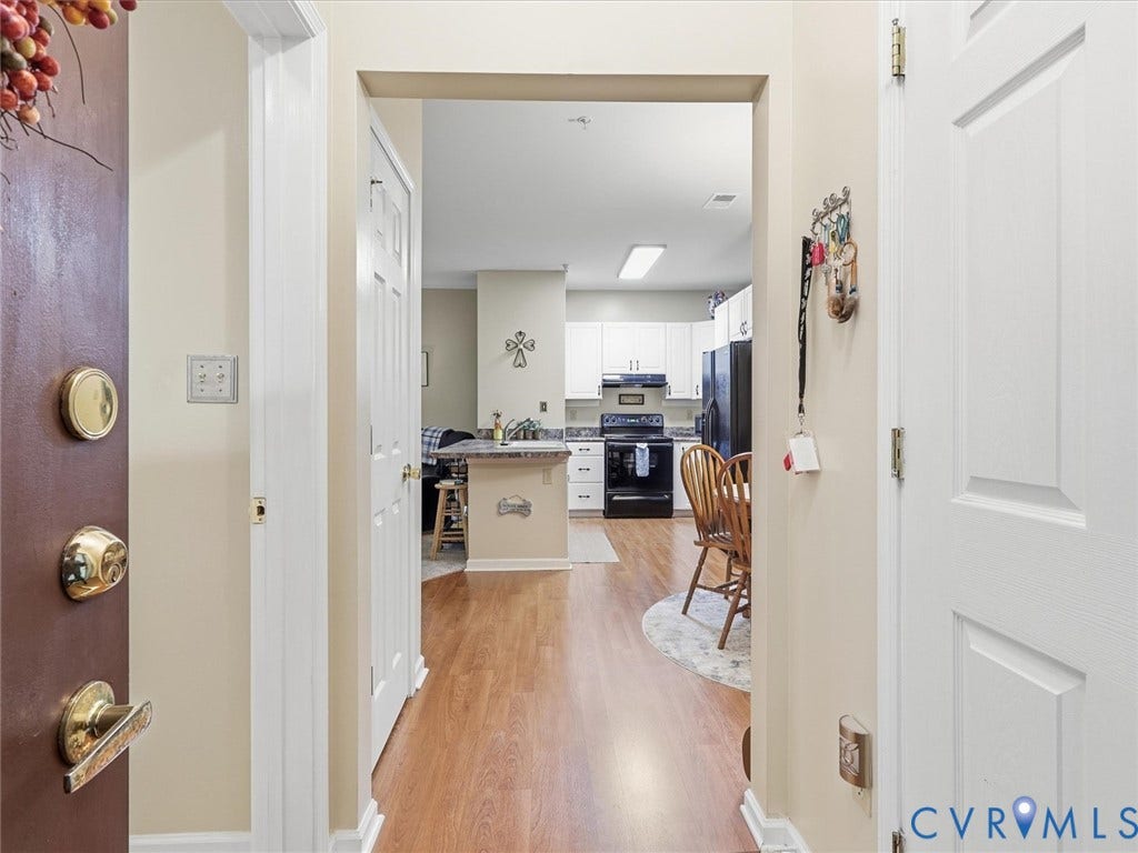 Laminat flooring, white paneled doors, and a kitchen featuring white cabinetry, black appliances, and a breakfast bar