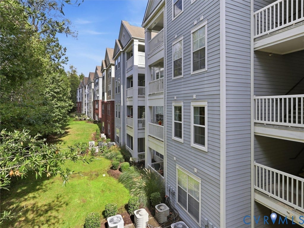Multi-story residential building with light blue siding, white-trimmed windows, and private balconies