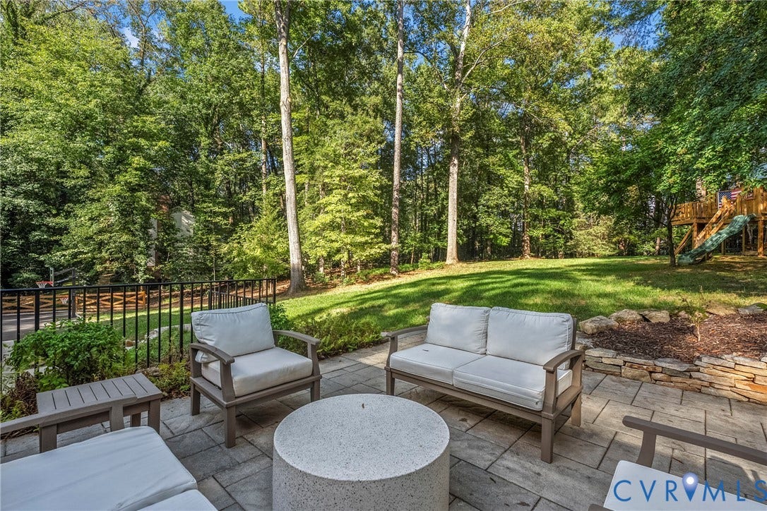 Paver patio with a stone retaining wall and a spacious lawn