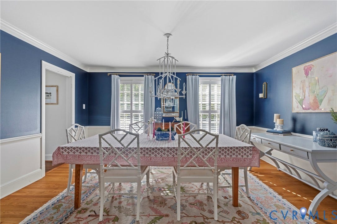 Hardwood flooring, white crown molding, wall paneling, and an elegant chandelier