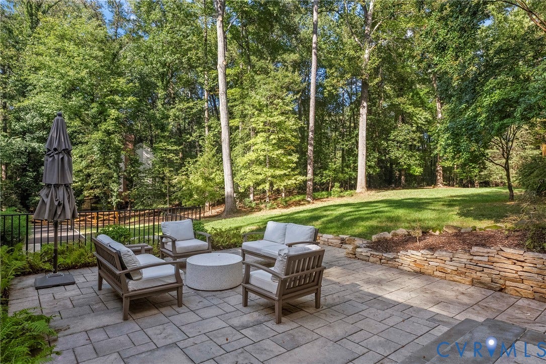 Paver patio with a stone retaining wall and an expansive grassy area