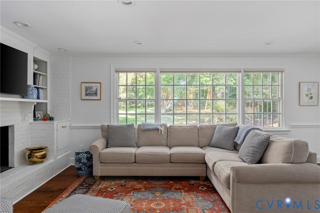 Living space featuring recessed lighting, extensive window banks, wood-finish flooring, and a white painted brick fireplace with built-in cabinetry