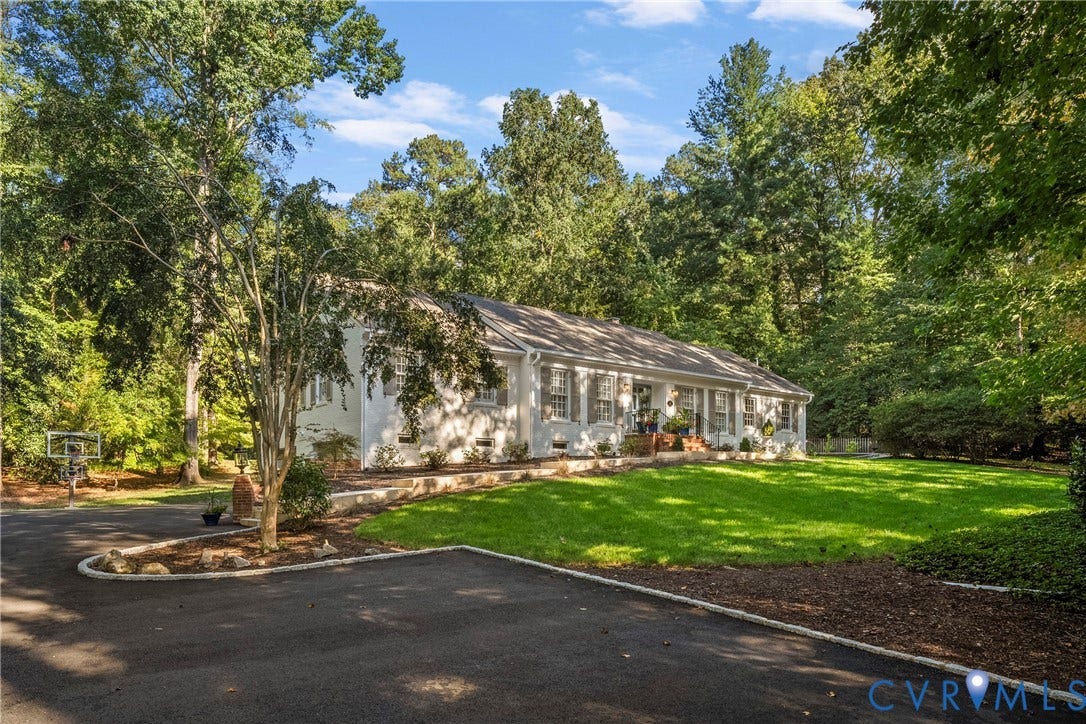 Single-story residence with a paved driveway, front lawn, and mature trees