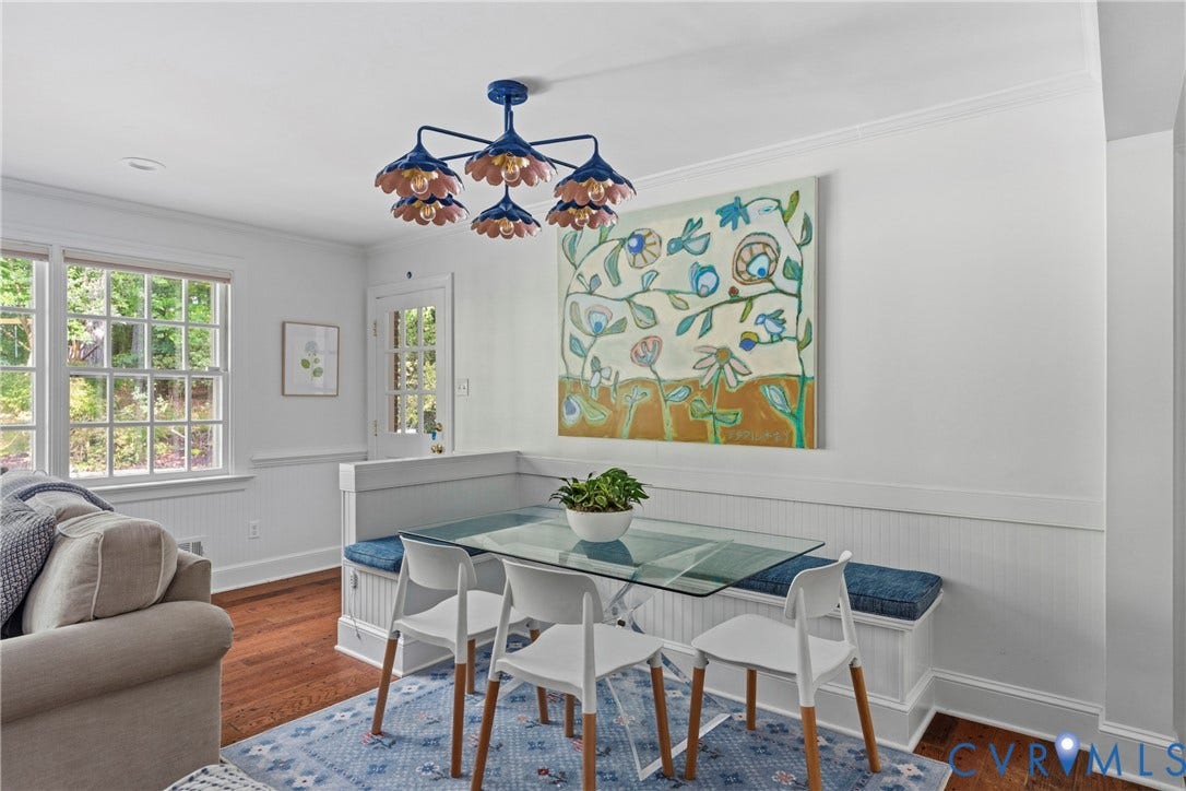 Hardwood flooring, built-in banquette seating, a glass-top table, and a decorative chandelier
