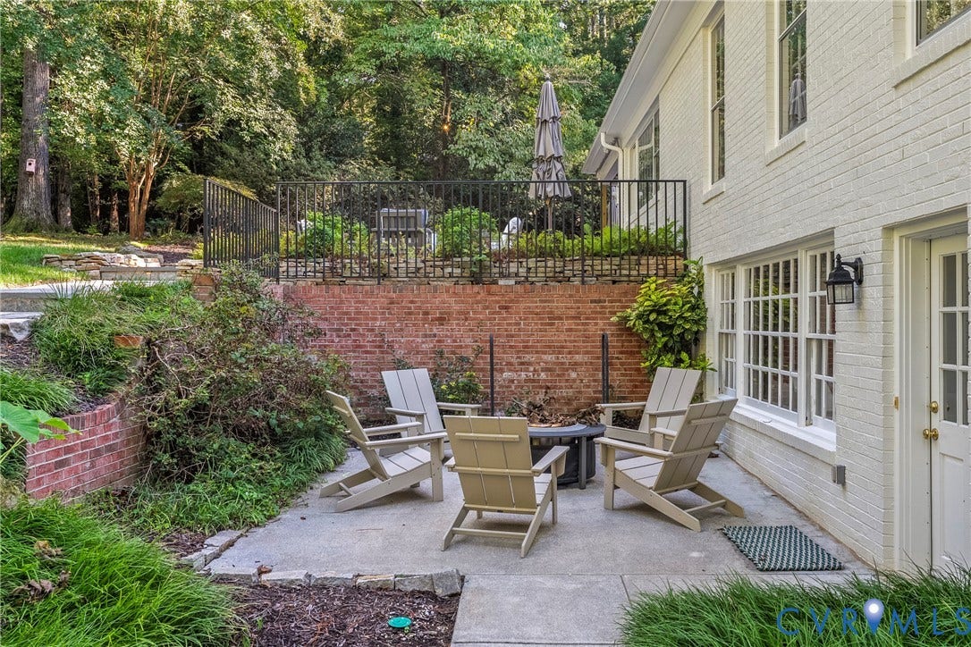 Exterior patio with concrete hardscaping, brick retaining wall, and painted brick facade