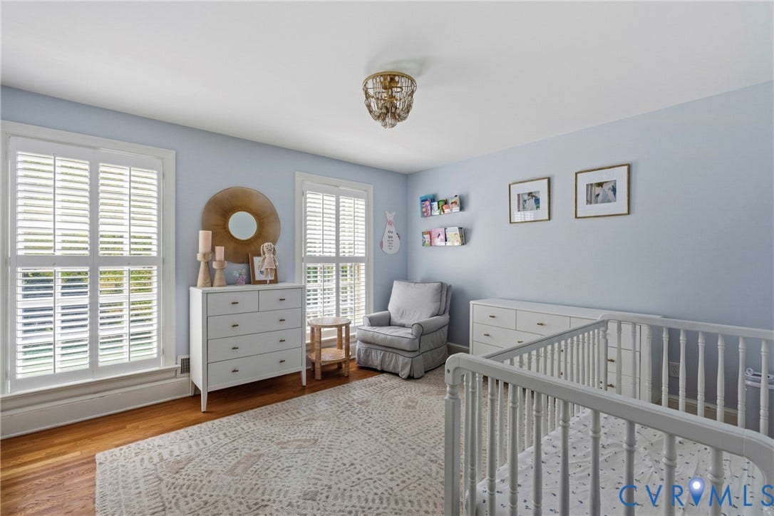 Hardwood flooring, two windows with plantation shutters, ceiling-mounted light fixture, and light-toned wall paint