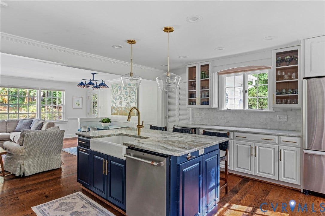 Kitchen island with a farmhouse sink and brass faucet, complemented by white cabinetry and stainless-steel appliances
