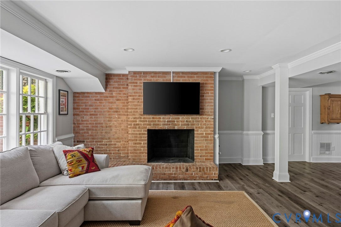 Brick fireplace with white mantel, recessed lighting, wood-finish flooring, and wainscoting
