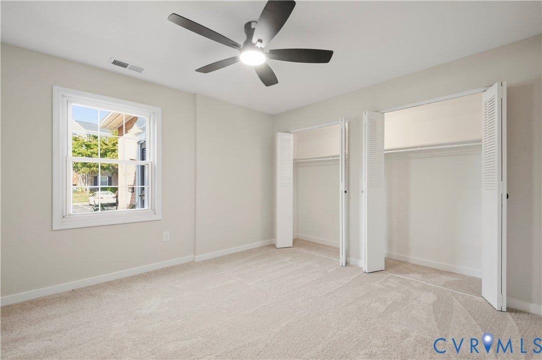 Plush carpeting, a ceiling fan with integrated lighting, a double-hung window, and bi-fold closet doors