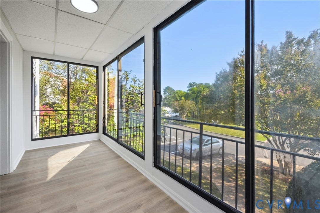 Enclosed porch featuring wood-finish flooring, extensive windows with black frames, a drop ceiling, and a flush mount light fixture