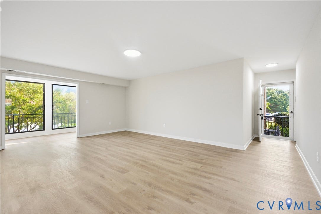 Spacious living area featuring wood-finish flooring, recessed lighting, and a private balcony with black metal railing