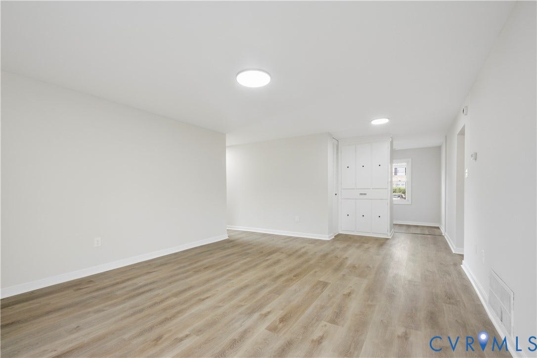 Expansive room with wood-finish flooring, white walls, and recessed lighting