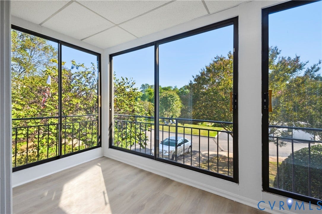 Expansive windows featuring black framing, light wood-finish flooring, and a white ceiling