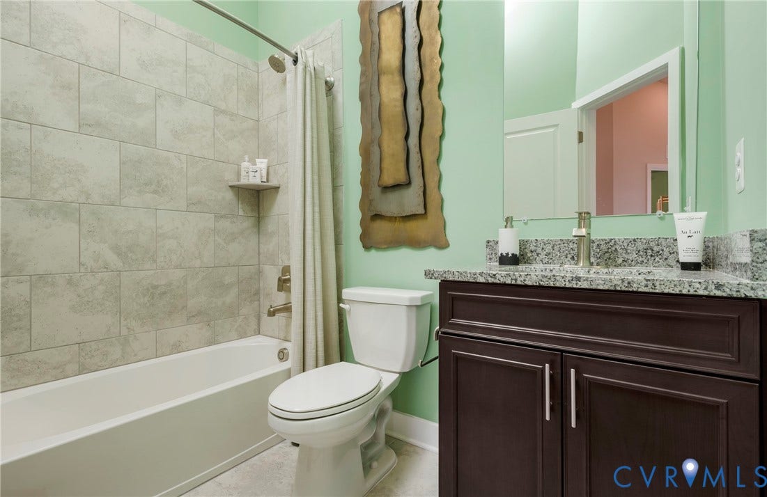 Contemporary bathroom featuring a dark wood-finish vanity with granite countertop, undermount sink, and brushed nickel faucet
