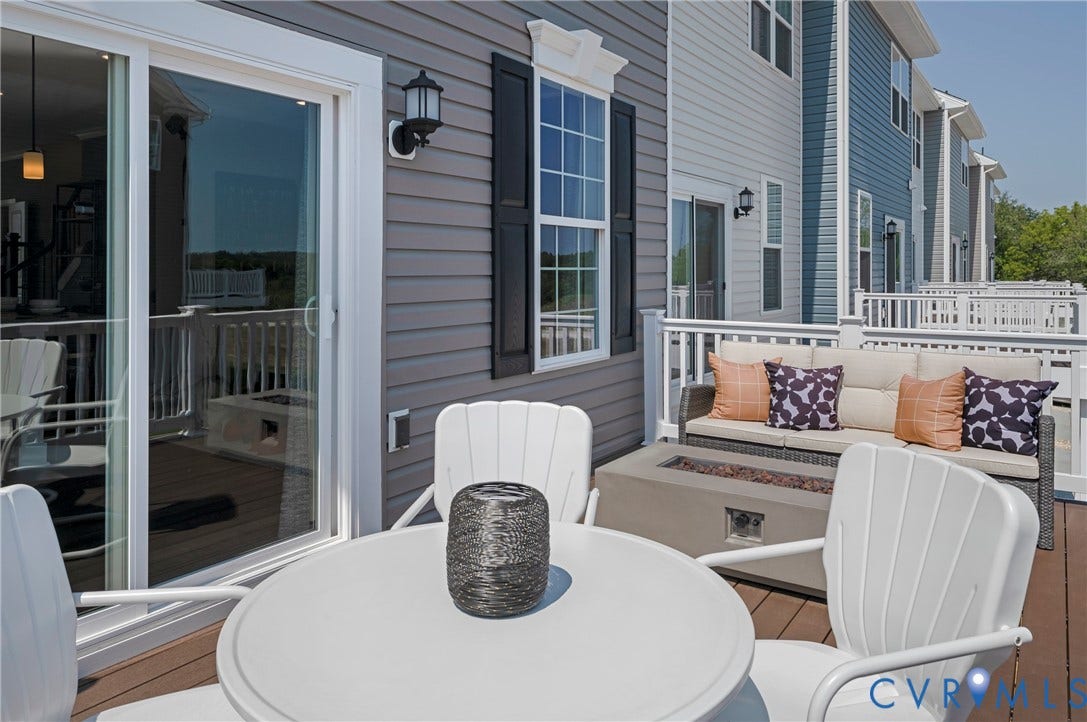 Expansive exterior deck with wood-finish flooring, white railing, and a built-in outdoor fire pit