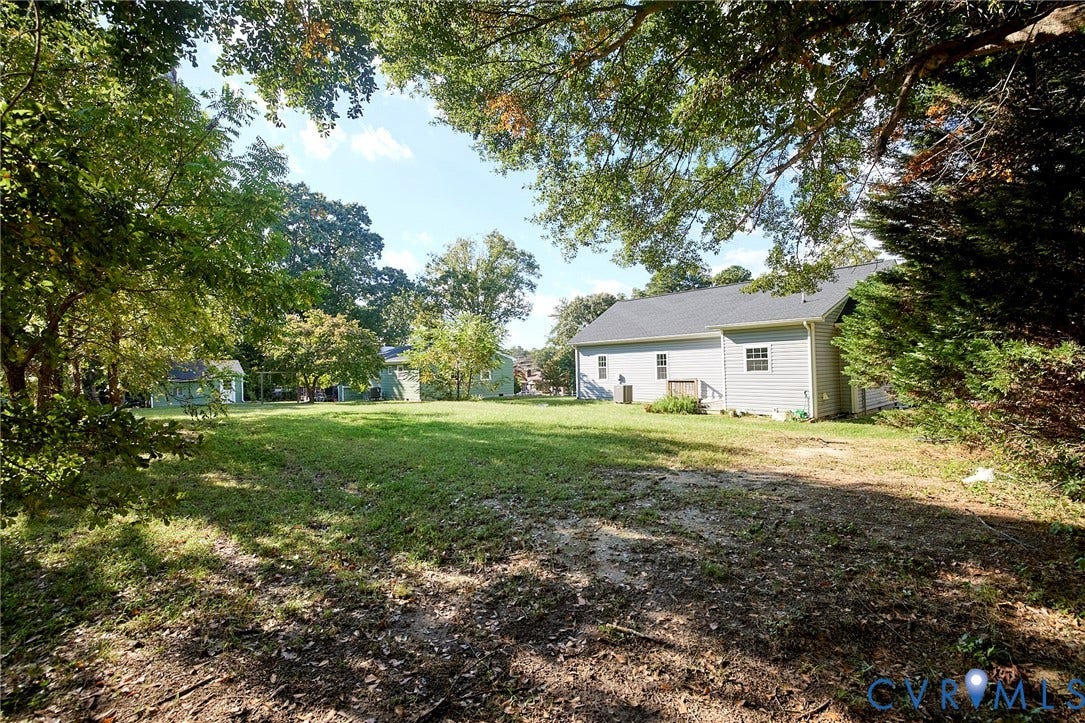 2421 Buena Vista Boulevard, Chester, VA 23831 Expansive green space with mature trees, a light-colored siding structure, and a dark-shingled roof
