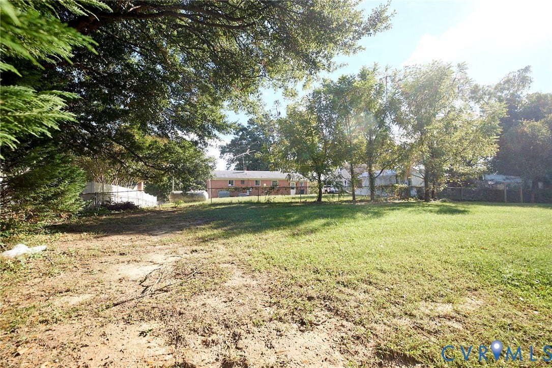 2421 Buena Vista Boulevard, Chester, VA 23831 Expansive outdoor space featuring a large grassy area, mature trees, and partial fencing
