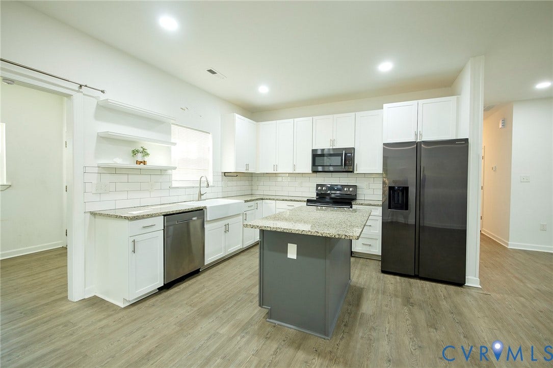 2421 Buena Vista Boulevard, Chester, VA 23831 Bright kitchen featuring white cabinetry, subway tile backsplash, a farmhouse sink, stainless steel appliances, and wood-finish flooring