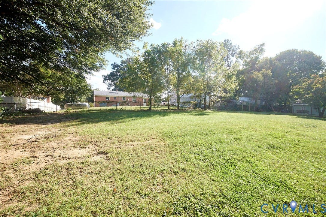 2421 Buena Vista Boulevard, Chester, VA 23831 Expansive lot featuring a blend of manicured lawn and natural ground cover, mature trees, and a chain-link fence border