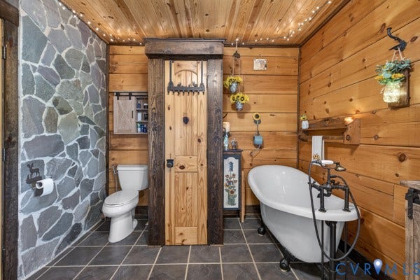 Clawfoot tub, wood walls, a stone-accented wall, wood-finish ceiling