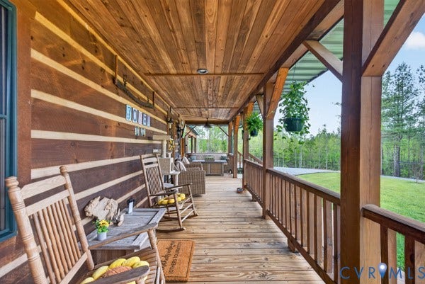 Expansive covered porch featuring wood-finish decking, wood-plank ceiling, and wood-beam supports