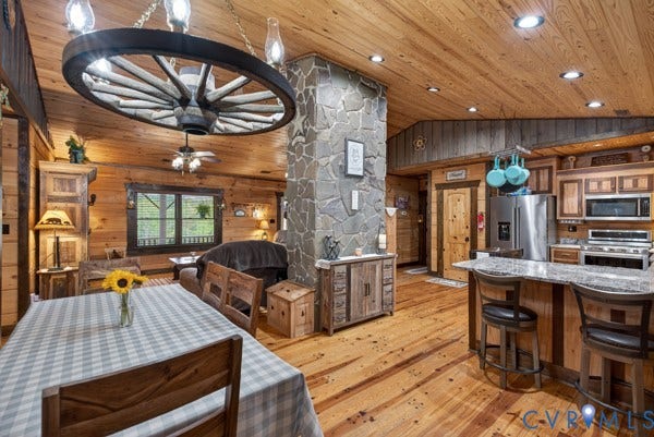 Wood-paneled ceilings, wood-finish flooring, a stone-clad pillar, and a kitchen island with seating